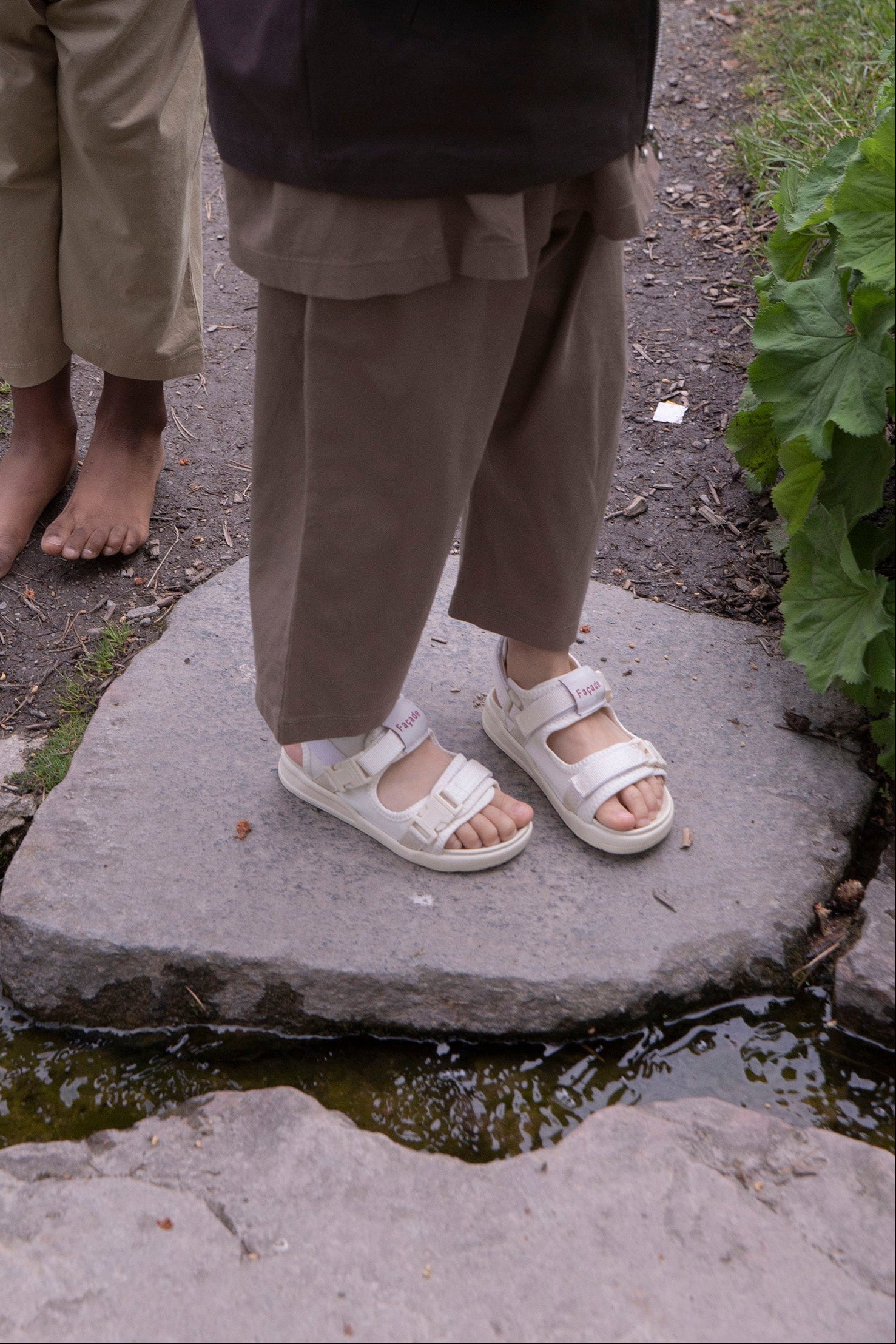 Two people standing on a stone path with one person wearing sandals.
